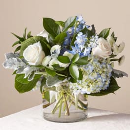 White roses and blue flowers in a clear glass vase