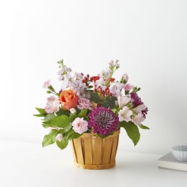 Mixed pink and purple flowers in a wooden basket