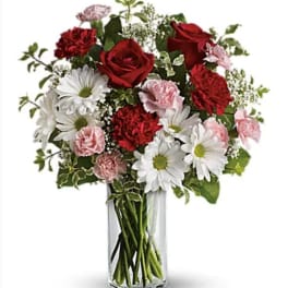 Bouquet of red roses, white daisies, and pink carnations in a clear glass vase