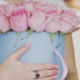 Pink roses arranged in a light blue hatbox with a ribbon handle
