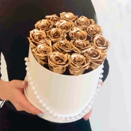 Gold roses arranged in a white round box with pearl trim