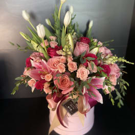 Pink and white floral arrangement in a round hat box