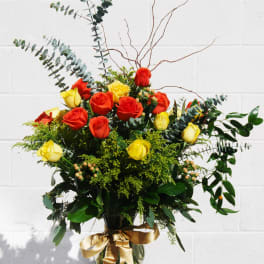 Bouquet of red and yellow roses in a glass vase with a gold ribbon