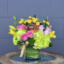Bouquet of yellow and pink roses with lime hydrangeas in a green vase