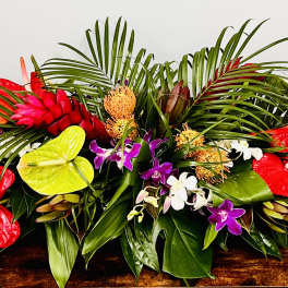 Tropical floral arrangement with red anthuriums, orchids, and palm fronds