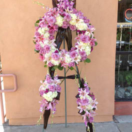 Standing floral wreath with pink roses, lilies, and white blooms on an easel