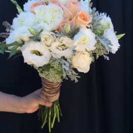 Handheld bouquet of white and peach roses with white blooms