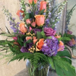 Tall bouquet of peach roses and purple hydrangeas in a glass vase