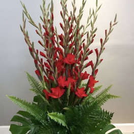 Tall red floral arrangement with tropical greenery in a black container