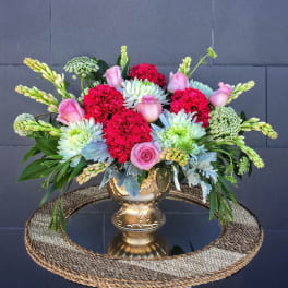Mixed bouquet in a gold vase with pink roses and red carnations
