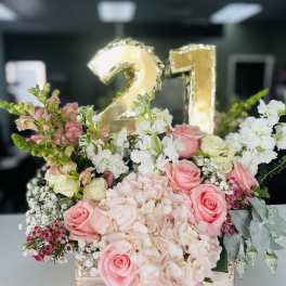 Pink and white floral arrangement with a gold "21" balloon