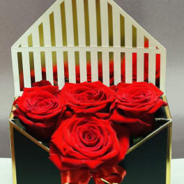 Four red roses in a black gift box with a red ribbon