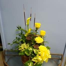 Yellow roses in a vase with tall incense sticks and a bright ribbon
