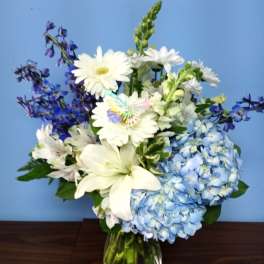 White daisies and blue hydrangeas in a glass vase