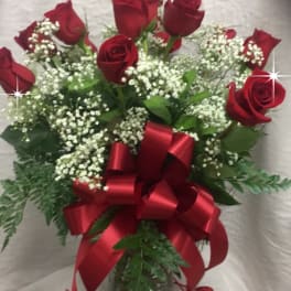 Bouquet of red roses with baby's breath in a glass vase and red ribbon