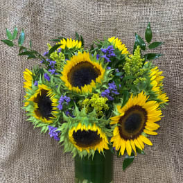 Sunflower bouquet in a glass vase with purple filler flowers