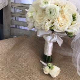 White bridal bouquet with roses and ranunculus, tied with satin ribbon