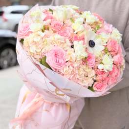 Pink and white bouquet of roses and hydrangeas wrapped in pale pink paper