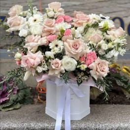 Large pastel bouquet of roses, daisies, and white blooms in a white box with ribbon