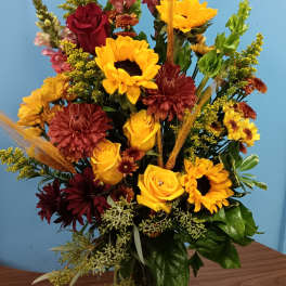 Mixed bouquet of sunflowers, roses, and chrysanthemums in a glass vase