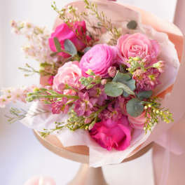 Pink rose and ranunculus bouquet wrapped in pale paper