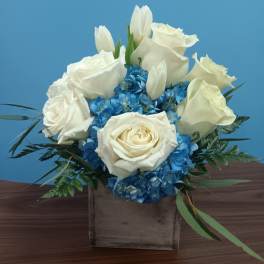White roses and blue hydrangeas in a square wooden box