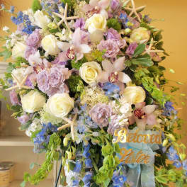 Large pastel floral standing spray with roses, orchids, and blue flowers