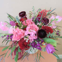 Mixed bouquet of pink, red, and purple flowers with greenery