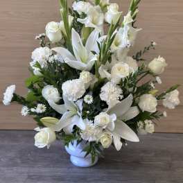 White lilies and roses arranged in a white vase