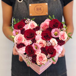 Heart-shaped box of red and pink roses held by a person