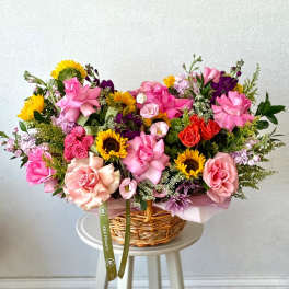 Mixed bouquet in a wicker basket with pink roses and sunflowers