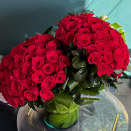 Two large bouquets of red roses in a glass vase