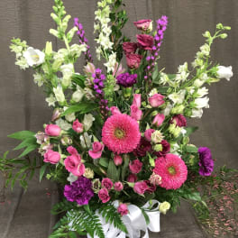Pink and white mixed flower arrangement in a glass vase with a white ribbon