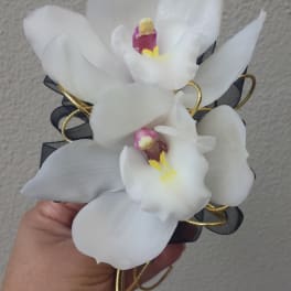 White orchid corsage with black ribbon and gold wire accents
