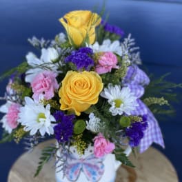 Bouquet of yellow roses, white daisies, and pink carnations in a white vase