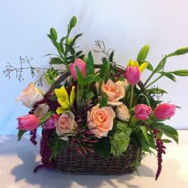 Basket arrangement of pink and peach roses with tulips and lilies
