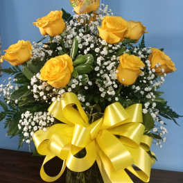 Yellow roses with baby's breath in a glass vase and yellow ribbon