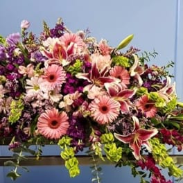 Large pink and purple floral arrangement on a table beside a lantern