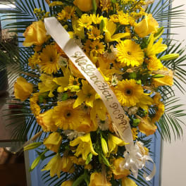 Tall yellow floral standing spray with a white ribbon on an easel