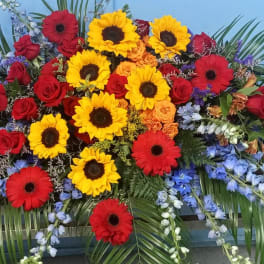 Large casket spray with red roses, yellow sunflowers, and red gerbera daisies
