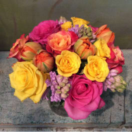 Bouquet of multicolored roses with purple filler flowers in a glass vase