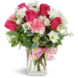 Pink roses and white daisies in a clear glass vase with a pink ribbon