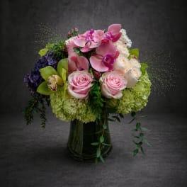 Pink and white floral arrangement in a dark glass vase