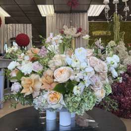 Large pastel floral arrangement with roses and orchids in white cylinders