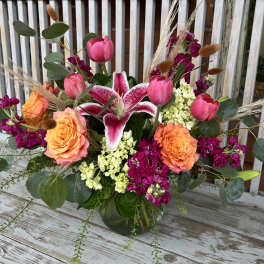 Bouquet of pink lilies, roses, and tulips in a glass vase