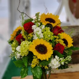 Bouquet of red roses and yellow sunflowers in a glass vase