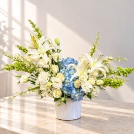 White lilies and blue hydrangeas in a white vase
