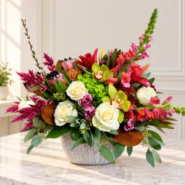 Mixed floral arrangement in a textured white vase with cream roses and bright pink blooms
