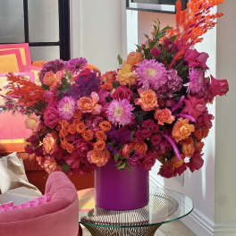 Large bouquet of pink, orange, and purple flowers in a magenta vase