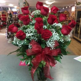 Red roses arranged in a clear vase with a red ribbon bow